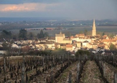 Vue sur le village de Meursault, des vignes sous le ciel noir. Une éclaircie sur le village où l'on aperçoit les toits dorés de la Bourgogne